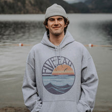 Load image into Gallery viewer, Model wearing grey hooded sweatshirt with Retro Sunset design.  Mountain Lake scenery in the background.